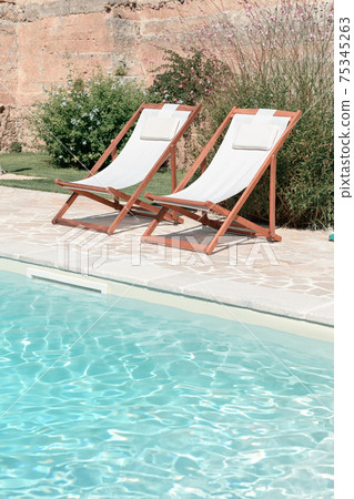 Swim pool with clear blue water and two sun bed on sunny day in a yard Swim pool with clear blue water and two sun bed on sunny day in a yard 75345263