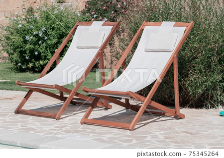 Swim pool with clear blue water and two sun bed on sunny day in a yard Swim pool with clear blue water and two sun bed on sunny day in a yard 75345264
