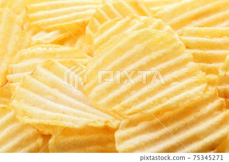 Yellow corrugated salted potato chips as food background Yellow corrugated salted potato chips as food background 75345271