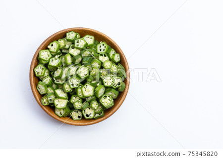 Fresh okra slices in wooden bowl on white Fresh okra slices in wooden bowl on white 75345820