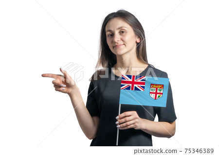 Happy young white woman holding flag Fiji and points to the left isolated on a white background Happy young white woman holding flag Fiji and points to the left isolated on a white background 75346389