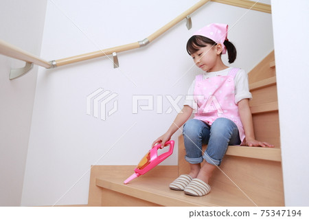 A 5-year-old girl helping with cleaning with a handy cleaner A 5-year-old girl helping with cleaning with a handy cleaner 75347194