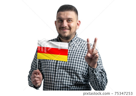 White guy holding a flag of South Ossetia and shows two fingers isolated on a white background White guy holding a flag of South Ossetia and shows two fingers isolated on a white background 75347253