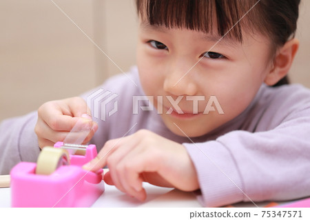 Girl who cuts and works on cellophane tape Girl who cuts and works on cellophane tape 75347571