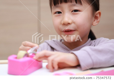 Girl who cuts and works on cellophane tape Girl who cuts and works on cellophane tape 75347572