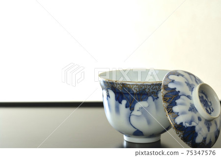Antique Imari ware ceramics. Lacquered bowl with lid on display shelf (bright background, soft focus) Antique Imari ware ceramics. Lacquered bowl with lid on display shelf (bright background, soft focus) 75347576