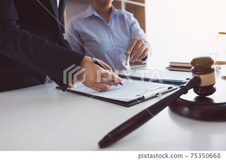 Legal advisor is explaining the offense under the law in the book at office. Legal advisor is explaining the offense under the law in the book at office. 75350668