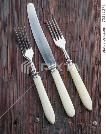 Vintage forks and knife on old wooden texture Vintage forks and knife on old wooden texture 75351378