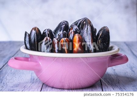 Mussels with parsley in a bowl on a wooden board. Seafood. 75354176