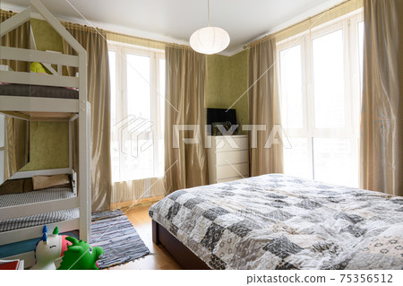 Bedroom interior with large double bed, bunk cot and two large stained glass windows 75356512