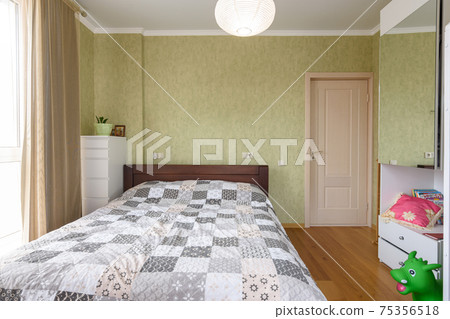 Bedroom interior with a large double bed and a wardrobe with a mirrored door Bedroom interior with a large double bed and a wardrobe with a mirrored door 75356518
