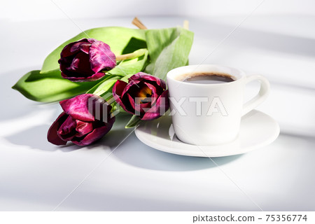 cup of blakc coffee and purple tulips 75356774