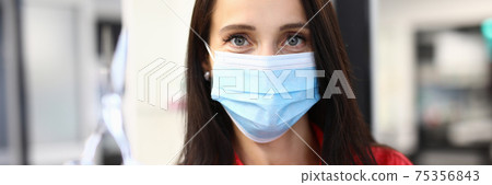 Woman hairdresser in medical mask holds scissors in hand Woman hairdresser in medical mask holds scissors in hand 75356843