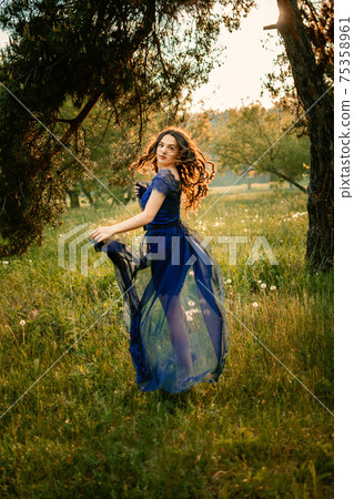 Party graduation prom fairytale concept. Beautiful brunette young woman in blue prom dress on nature background. Outdoor romantic portrait of brunette Latina Hispanic girl in long evening dress Party graduation prom fairytale concept. Beautiful brunette young woman in blue prom dress on nature background. Outdoor romantic portrait of brunette Latina Hispanic girl in long evening dress 75358961