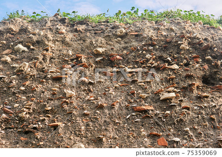 occupation earth - layers of ground with fragments of ancient pottery and shells under the sod layer 75359069