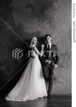 Cute wedding couple in interior of classic studio. They kiss and hug each other. 75359728