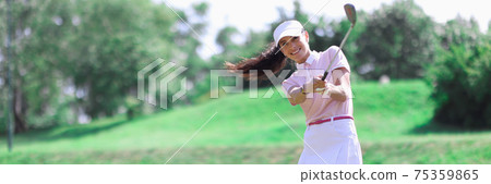 Woman golfer makes hit with golf club. 75359865