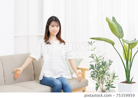 年輕女子坐在房間裡的沙發上,深吸一口氣 年輕女子坐在房間裡的沙發上,深吸一口氣 75359959