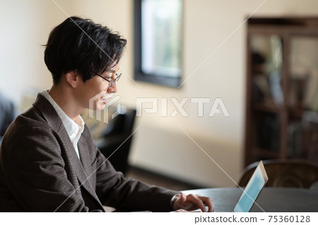 A man looking at a computer in the living room A man looking at a computer in the living room 75360128