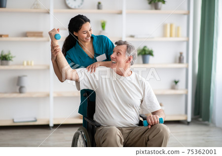 Rehabilitation of disabled people. Young physiotherapist helping senior male patient in wheelchair exercise at home Rehabilitation of disabled people. Young physiotherapist helping senior male patient in wheelchair exercise at home 75362001