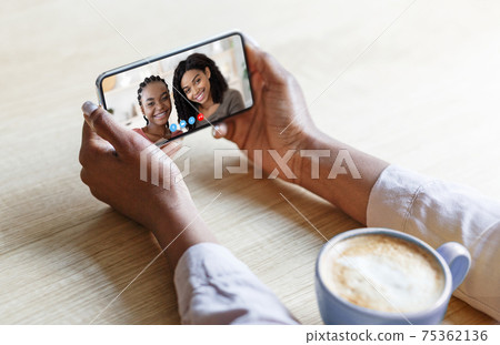 Young black lady with coffee speaking to her friends remotely, using smartphone to talk to family online, closeup 75362136