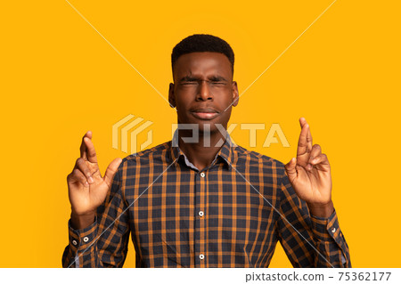 Making wish. Superstitious african american guy keeping his fingers crossed 75362177