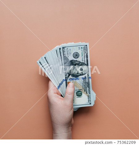 Bundle of dollars in hand on beige background 75362209