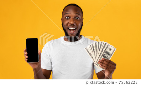 Excited African Guy Showing Smartphone Holding Money Over Yellow Background Excited African Guy Showing Smartphone Holding Money Over Yellow Background 75362225