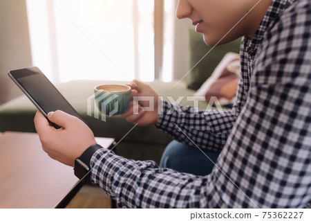 Smiling man reading smartphone, black screen and coffee cup. Blurred background Smiling man reading smartphone, black screen and coffee cup. Blurred background 75362227