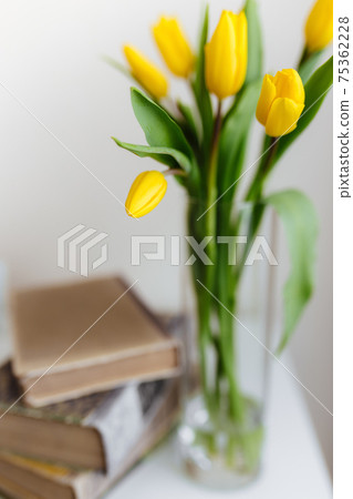 Bouquet of yellow tulip flowers in vase and books. Greeting card concept Bouquet of yellow tulip flowers in vase and books. Greeting card concept 75362228