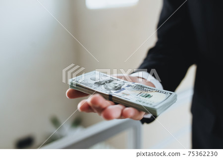 One hundred dollar bills money bundle, in hand of man in suit and white shirt 75362230