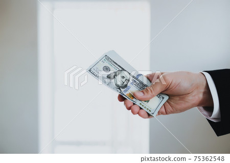 One hundred dollar bills money bundle, in hand of man in suit and white shirt 75362548