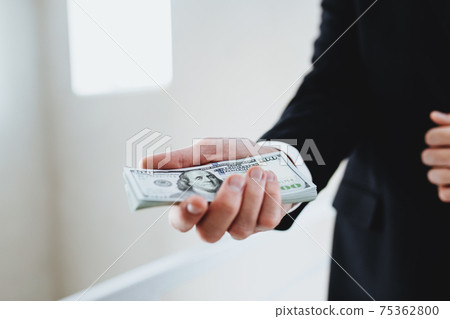 One hundred dollar bills money bundle, in hand of man in suit and white shirt One hundred dollar bills money bundle, in hand of man in suit and white shirt 75362800