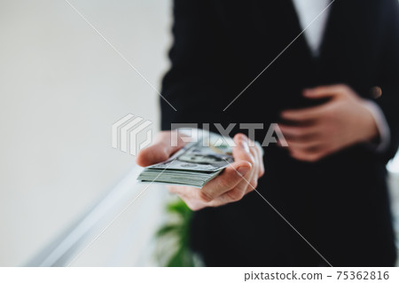 One hundred dollar bills money bundle, in hand of man in suit and white shirt 75362816