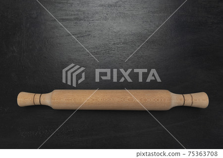 Wooden rolling pin on black background top view. 75363708