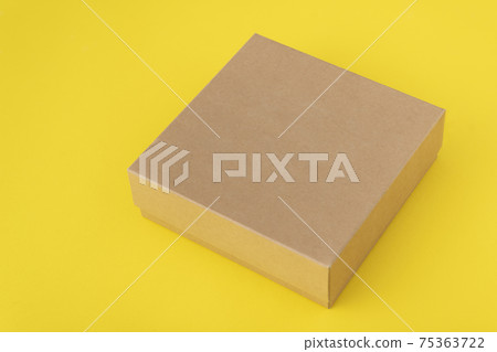 Square cardboard box on yellow background. Copy space. Mock up. 75363722