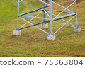 Lower part of a large electric support on a background of green grass 75363804