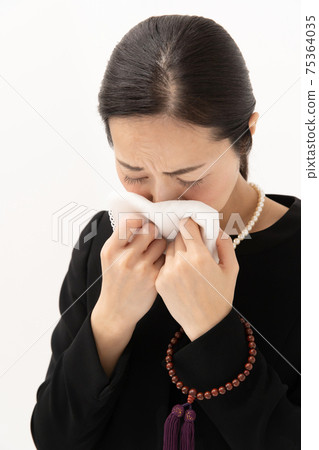 Woman in mourning wipes tears 75364035