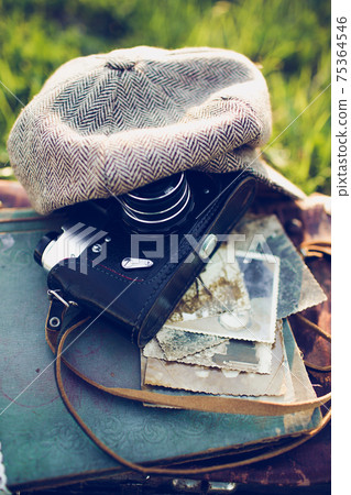 Close-up of an old camera with a vintage hat and retro photos on a wooden background. 75364546