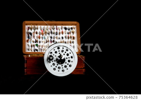 Wooden Fly Box and Fly Reel on a Black Background 75364628
