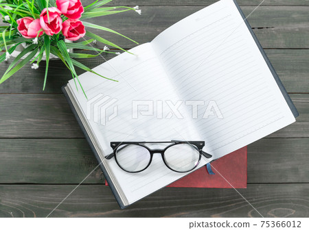 Reading glasses put on open book 75366012