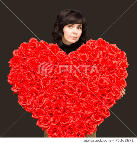 Beautiful brunette with a large bouquet of flowers in the shape of a heart Beautiful brunette with a large bouquet of flowers in the shape of a heart 75368671