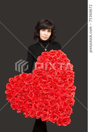 Beautiful brunette with a large bouquet of flowers in the shape of a heart Beautiful brunette with a large bouquet of flowers in the shape of a heart 75368672
