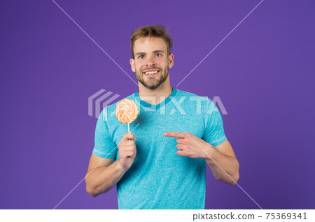 Sugar harmful for health. Guy hold lollipop candy violet  75369341