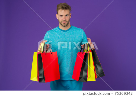 Man with shopping bags on violet background. Macho Man with shopping bags on violet background. Macho 75369342