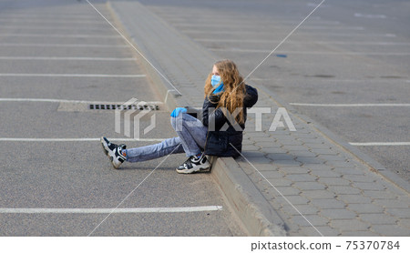 Portrait of sad Caucasian girl in face mask at the city and in the park outdoor. Coronavirus social distance quarantine. Portrait of sad Caucasian girl in face mask at the city and in the park outdoor. Coronavirus social distance quarantine. 75370784