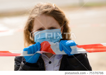 Portrait of sad caucasian child in face mask on closed playground outdoor. Coronavirus social distance quarantine. 75370786