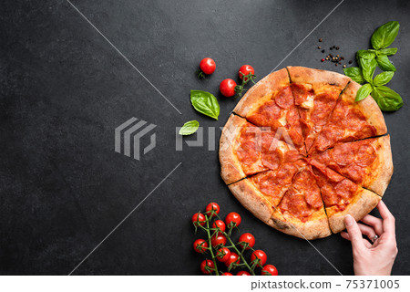 Hand taking slice of pepperoni pizza 75371005