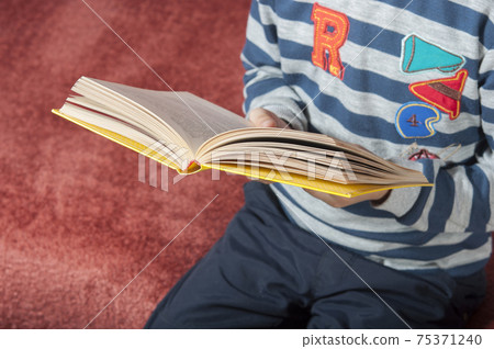 Kid with book at home. Kid with book at home. 75371240