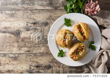 Stuffed potatoes with bacon and cheese on plate on wooden table Stuffed potatoes with bacon and cheese on plate on wooden table 75371920